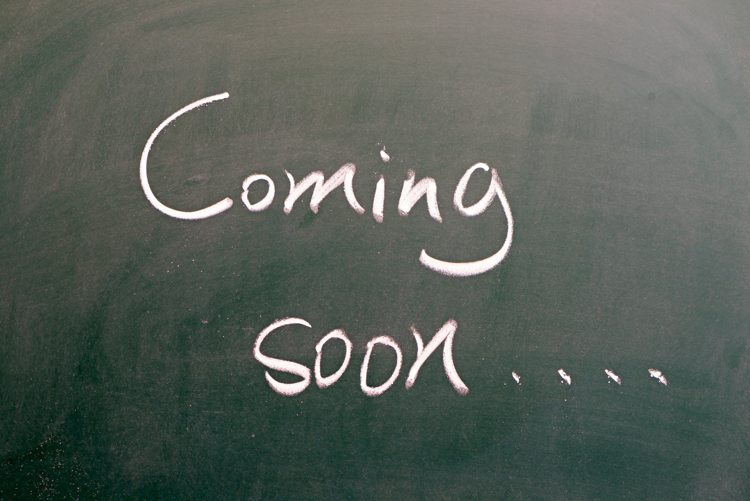 hand writing "coming soon" on blackboard